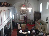 Gottesdienst in einer gut besetzten Kirche mit Kronleuchter
