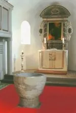 Der romanische Taufstein in Kelchform vor dem Altar der Böllberger Kirche