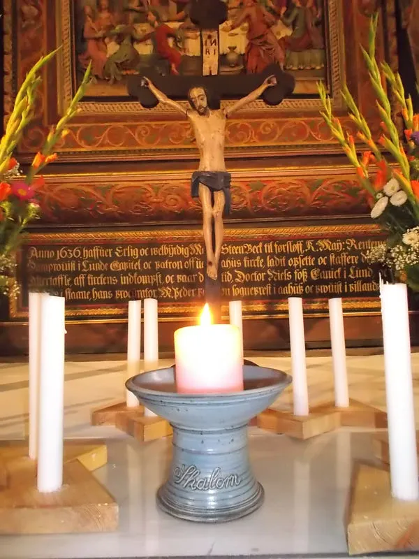 Die Partnerkerze in Åhus vor einem Altar mit Kruzifix und weiteren Kerzen